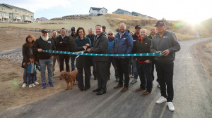 Members of the Herriman City Council and staff stand with representatives from Salt Lake County, construction crews, and other members of the public to ceremoniously cut the ribbon to celebrate the opening of Juniper Canyon's second phase.
